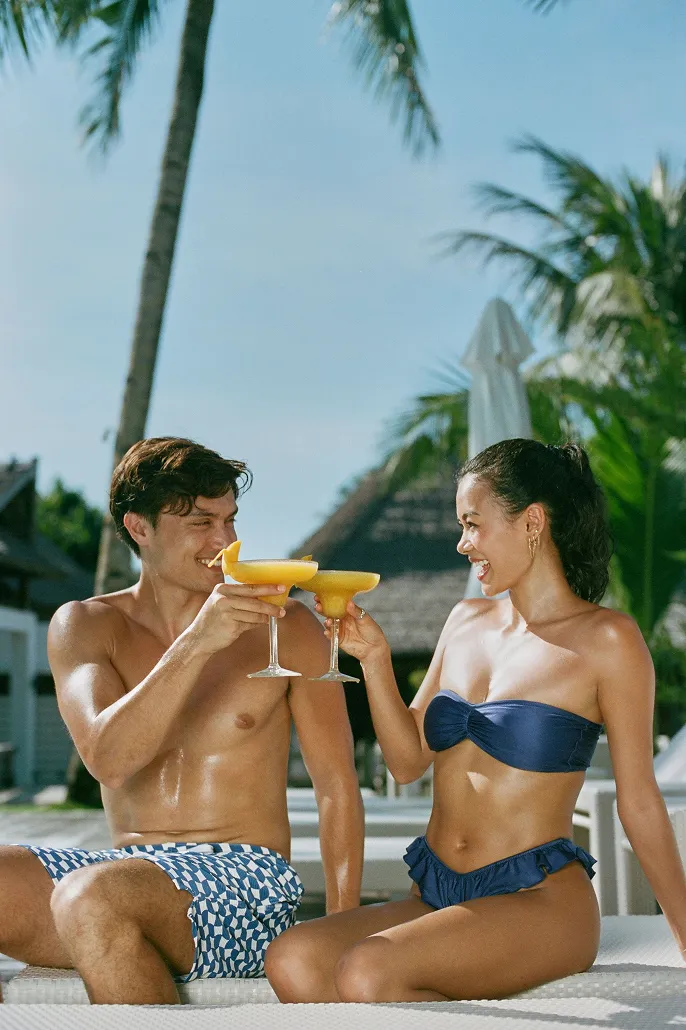 On Kelly (left) : Men’s Swim Shorts / Corfu Blue, On Ashley (right) : Nadia Top and Elsie Bottoms / Jazzy Blues Gloss