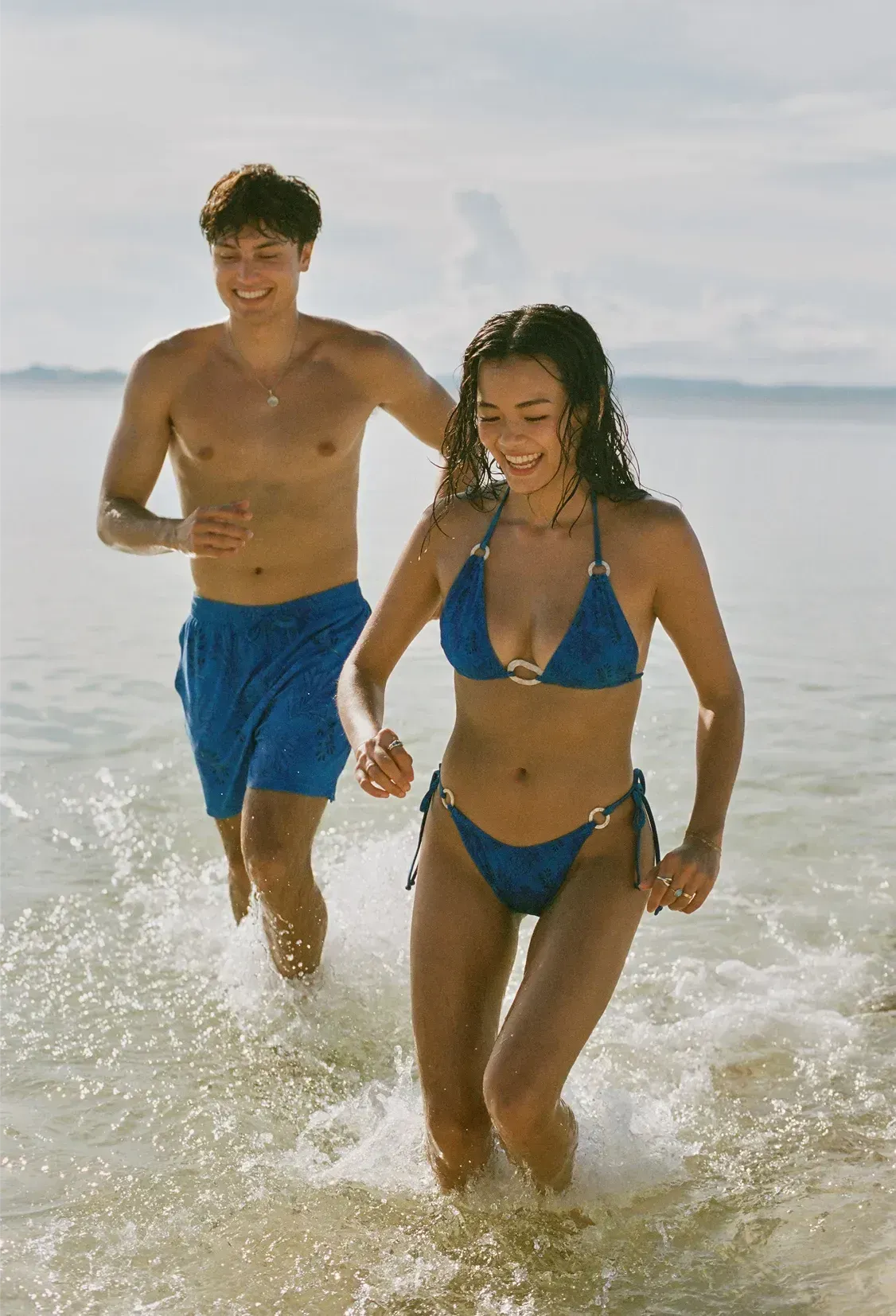 On Kelly (left) : Men’s Swim Shorts / Reef Blue, On Ashley (right) : Beatrice Ring Top and Pia Side-Ties Bottoms / Reef Blue
